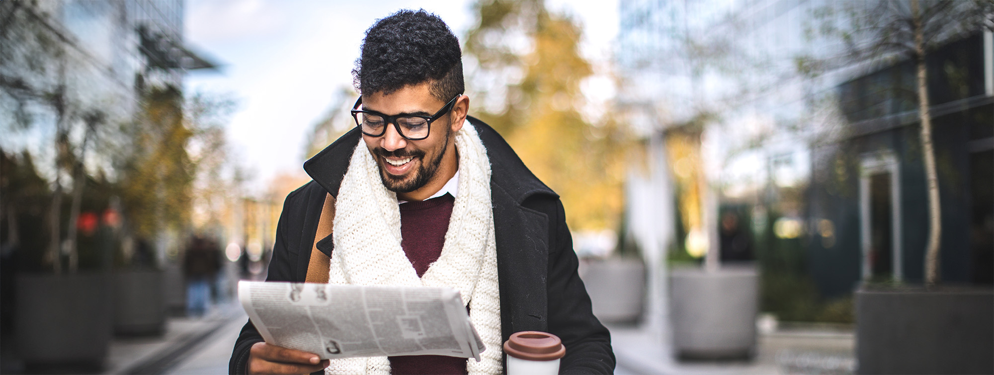 man wearing glasses reads a newspaper